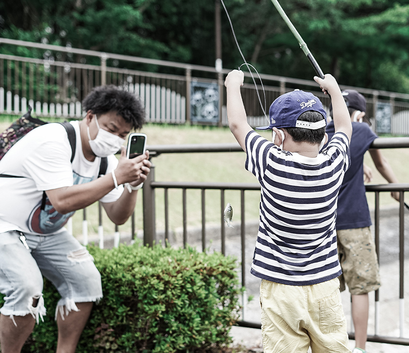 魚を釣った子供を撮影する親子の写真